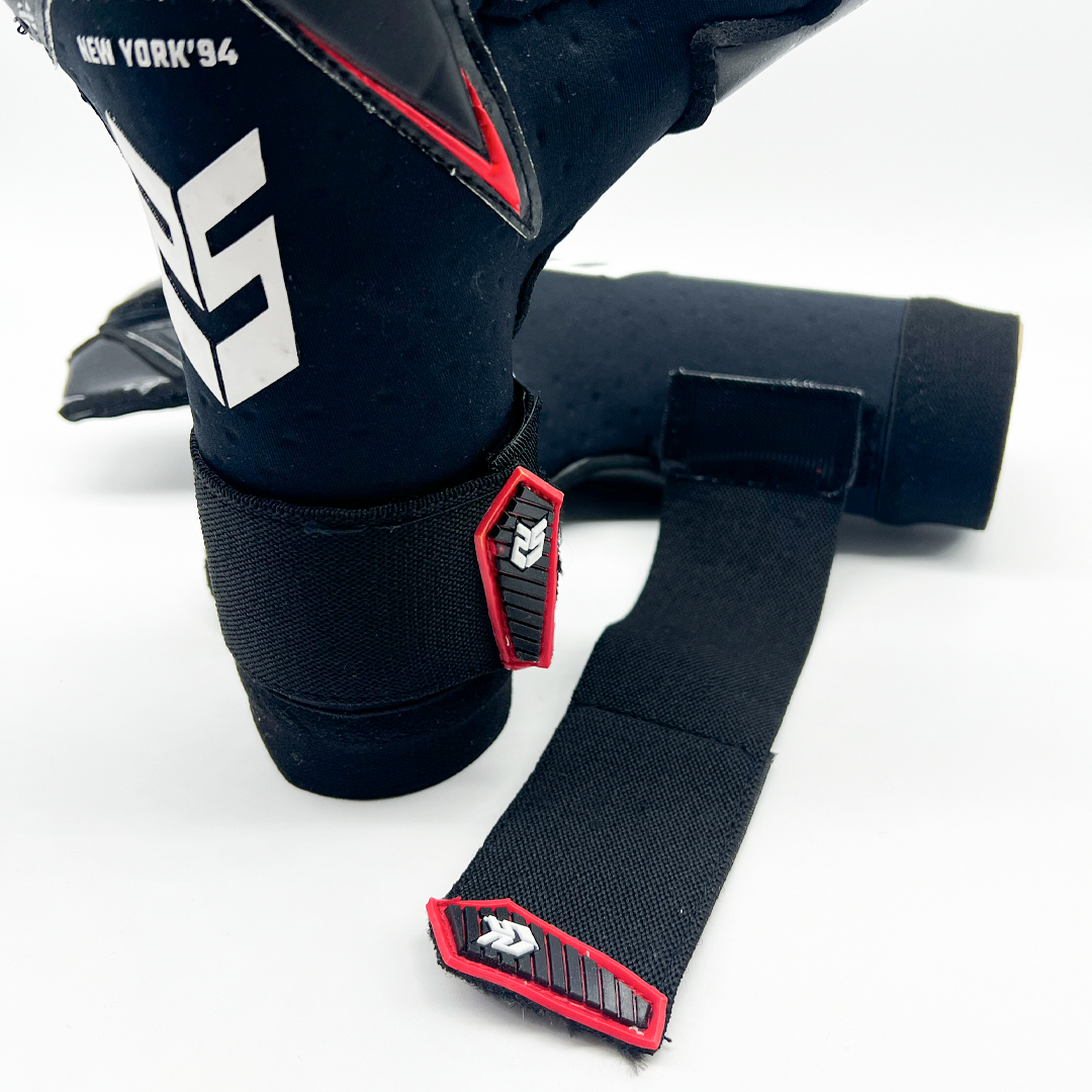 Guantes de Arquero New York '94 Contacgrip goalkeeper gloves in black with red and white details and wrist straps open on white background.